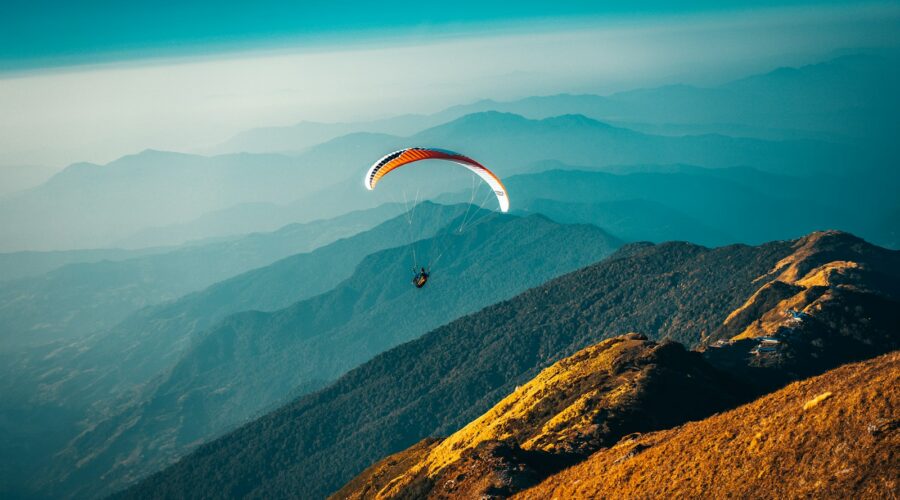 person in parachute over mountains during daytime