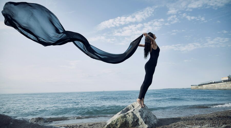 a woman standing on top of a rock near the ocean