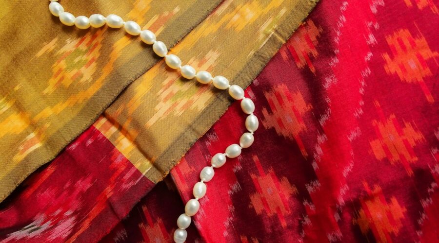 silver necklace on red textile