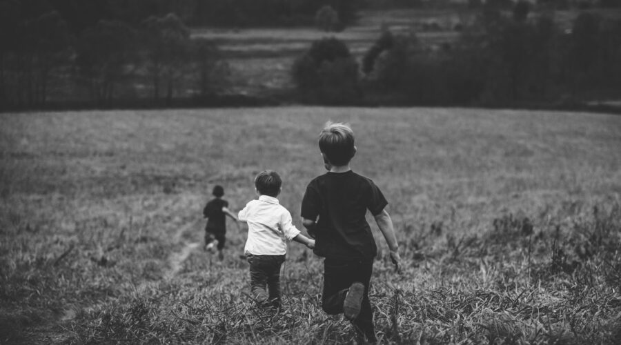 three boys running on field
