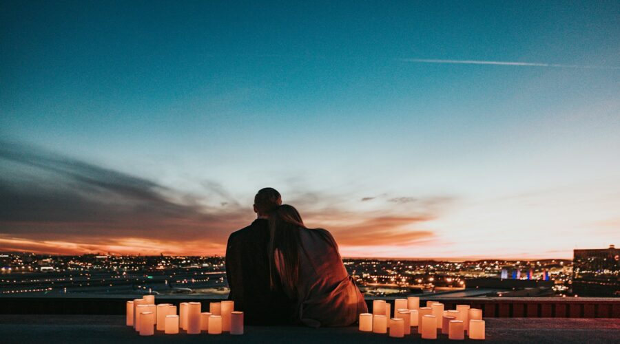 couple sitting on the field facing the city