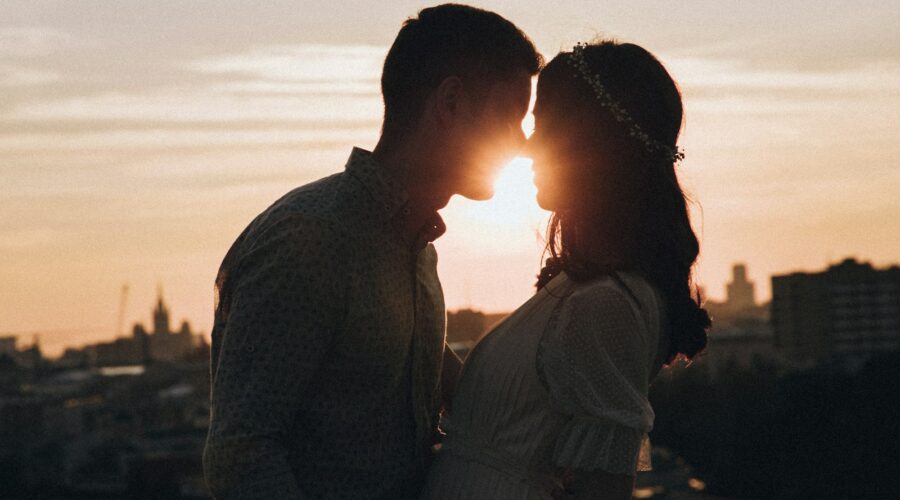 a man and a woman standing in front of a sunset